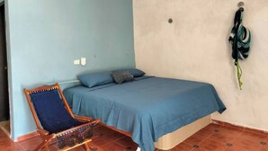 A bedroom with a bed, a chair, and a hanging item on the wall.