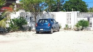 A blue car parked in front of a building with a sign that reads "PARKING" and an arrow pointing upwards.