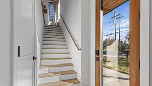 A staircase with wooden steps leading to a landing, a glass door, and a view of the outside. - Nashville house near Geodis Park with hot tub, game room, sleeps 12 (Nashville)