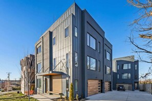 A modern two-story residential building with a flat roof, large windows, and a garage.