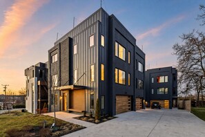 A modern two-story residential building with a garage, a driveway, and a well-maintained lawn. - Fall getaway: rooftop hot tub, poker room, sleeps 12 near Geodis Park (Nashville)