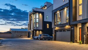 A modern multi-story residential building with large windows and a paved driveway.