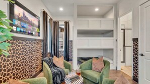 A modern living room with green sofas, a coffee table, and a mounted TV displaying a cityscape.