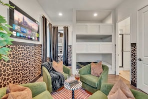A modern living room with green sofas, a coffee table, and a mounted TV displaying a cityscape.