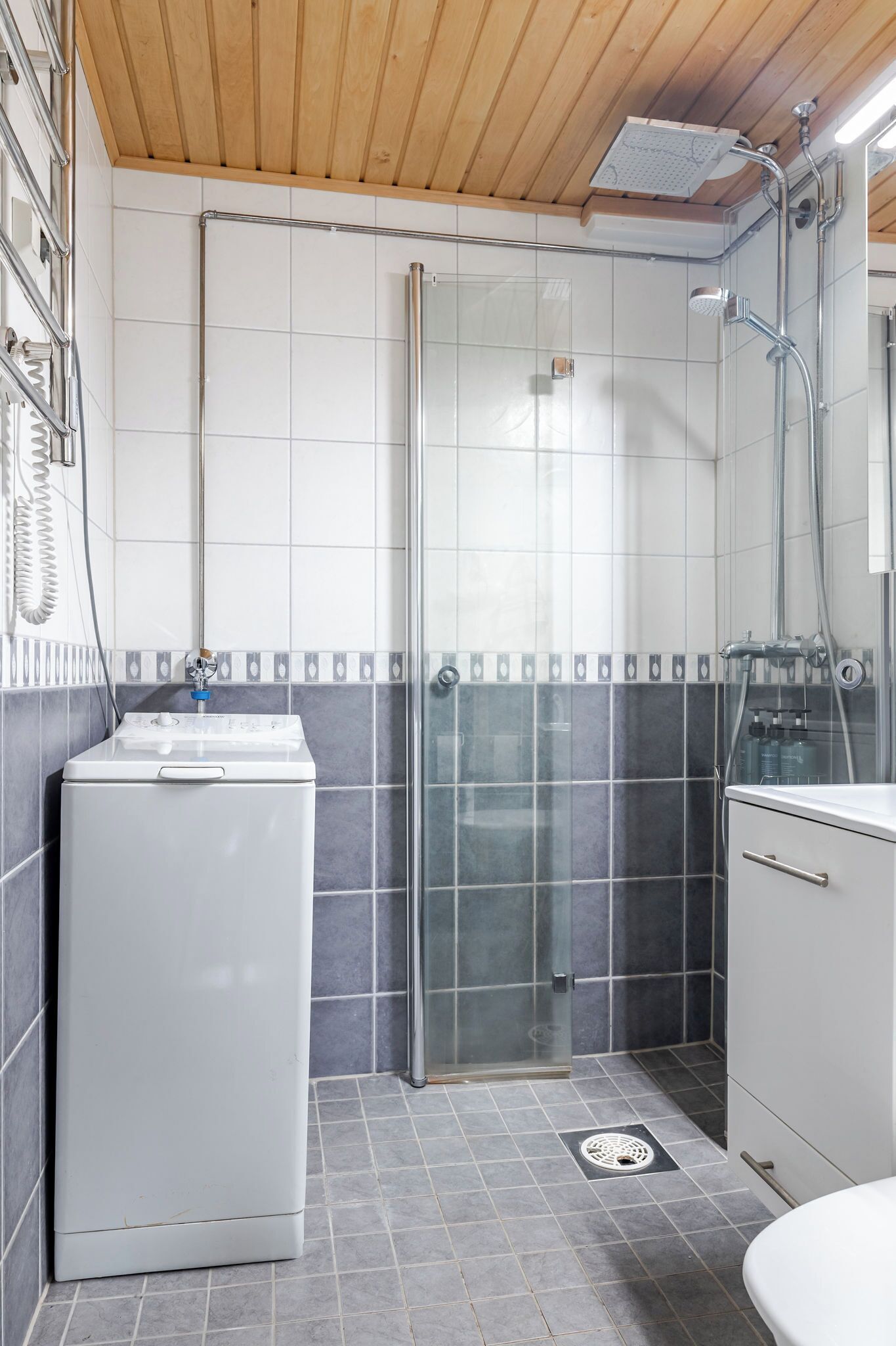 Une salle de bain avec une douche à parois de verre, un lave-linge blanc et des toilettes.