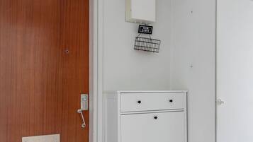 A room with a wooden door, a white cabinet with drawers, and a small sign above it.
