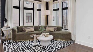 Un salon moderne avec un canapé vert, une table basse ronde et un tapis à motifs zébrés.
