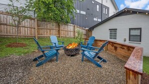Un patio al aire libre con sillas Adirondack, una chimenea y una terraza de madera.