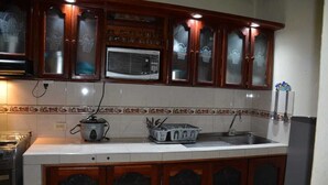 A kitchen with wooden cabinets, a microwave, a stove, and a sink. - Cozy Furnished Room + Breakfast (Medellín)