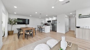 Une cuisine moderne avec des meubles blancs, un îlot central et un four à micro-ondes encastré.