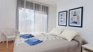Ein Schlafzimmer mit einem Bett, einem Sessel und zwei gerahmten Bildern an der Wand.