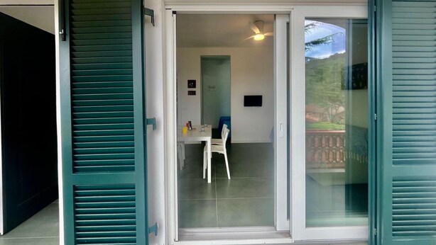 A modern room with a sliding glass door leading to a balcony. - Casa San Michele a Bagnaia (Portoferraio)