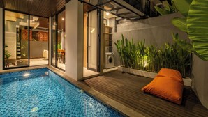 A modern indoor pool area with a wooden deck, a glass door leading to a room, and a potted plant. - Private Villa Ayra 8D 10min MelastiBeach (Ungasan)