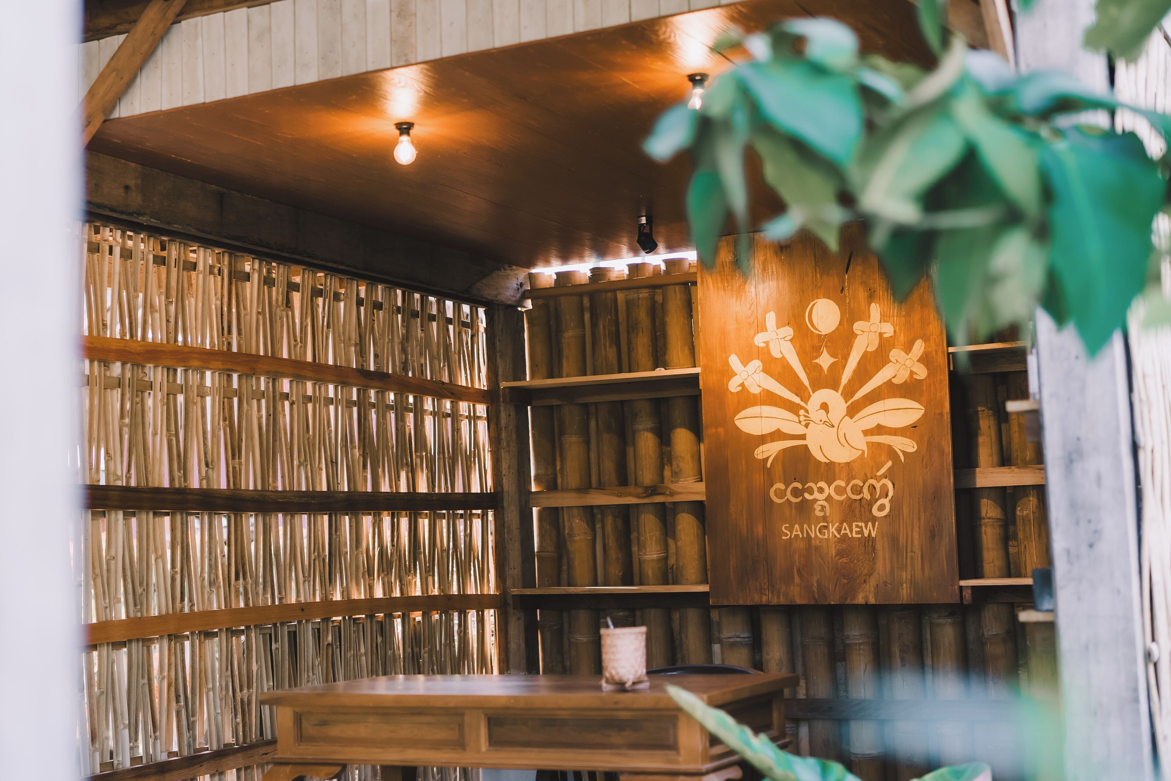 A room with bamboo walls, wooden shelves, and a table with a plant.