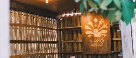 A room with bamboo walls, wooden shelves, and a table with a plant.