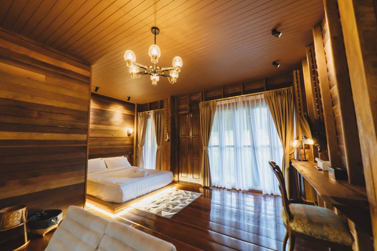 A wooden cabin-style room with a bed, a chair, a desk, and a chandelier.