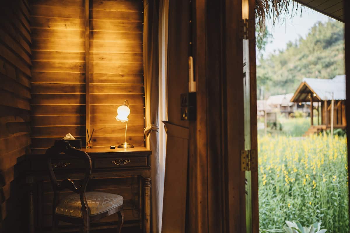 A wooden interior with a desk, chair, and a lamp.