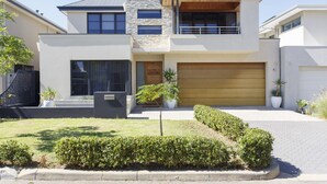 A modern two-story house with a stone facade, large windows, and a wooden garage door.