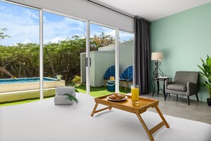 Een moderne kamer met een schuifglasdeur naar een zwembad, een eettafel met ontbijt en een lounge stoel.