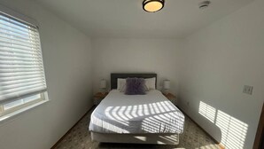 Camera da letto con un letto, due comodini, una lampada a soffitto e una finestra con persiane.