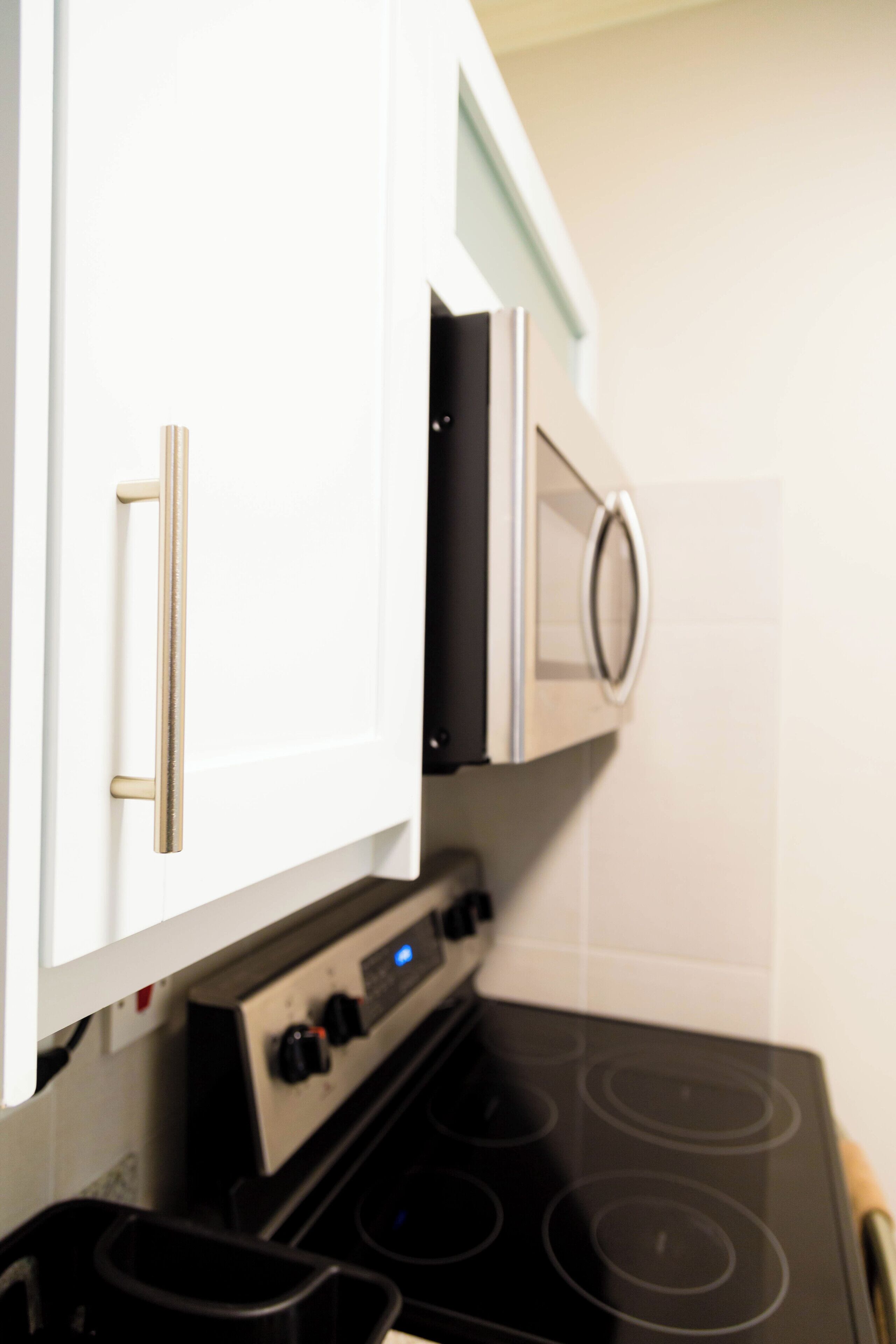 A kitchen with white cabinets, a stove, and a microwave.