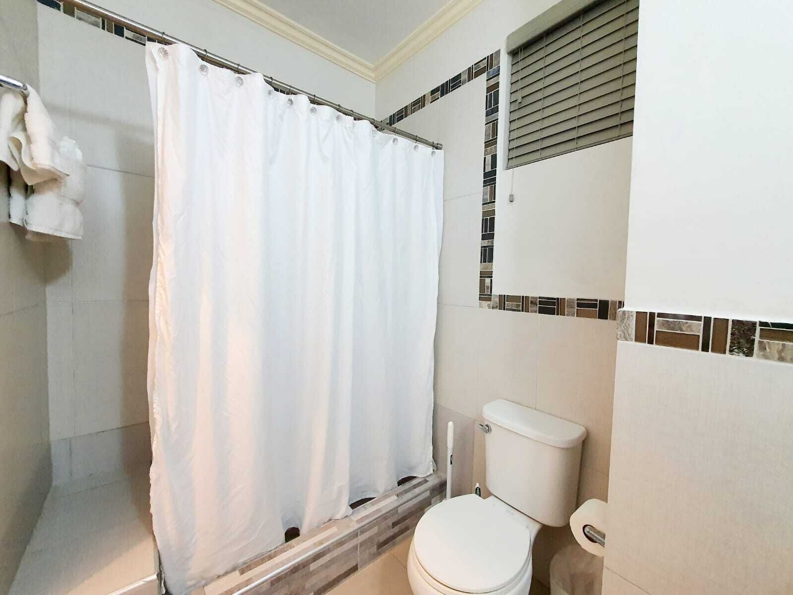 A bathroom with a shower curtain, a toilet, and tiled walls.