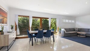 A modern living room with a dining area, a sofa, and a coffee table. - Wiltons Riverside family haven, pet friendly (Ocean Grove)
