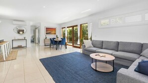 A modern living room with a grey sofa, a round coffee table, and a blue rug. - Wiltons Riverside family haven, pet friendly (Ocean Grove)