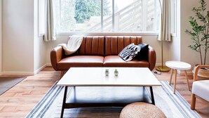 Un salon moderne avec un canapé en cuir marron, une table basse blanche et une petite table d’appoint.