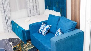 Una habitación con una cama, un sofá azul y una alfombra estampada.