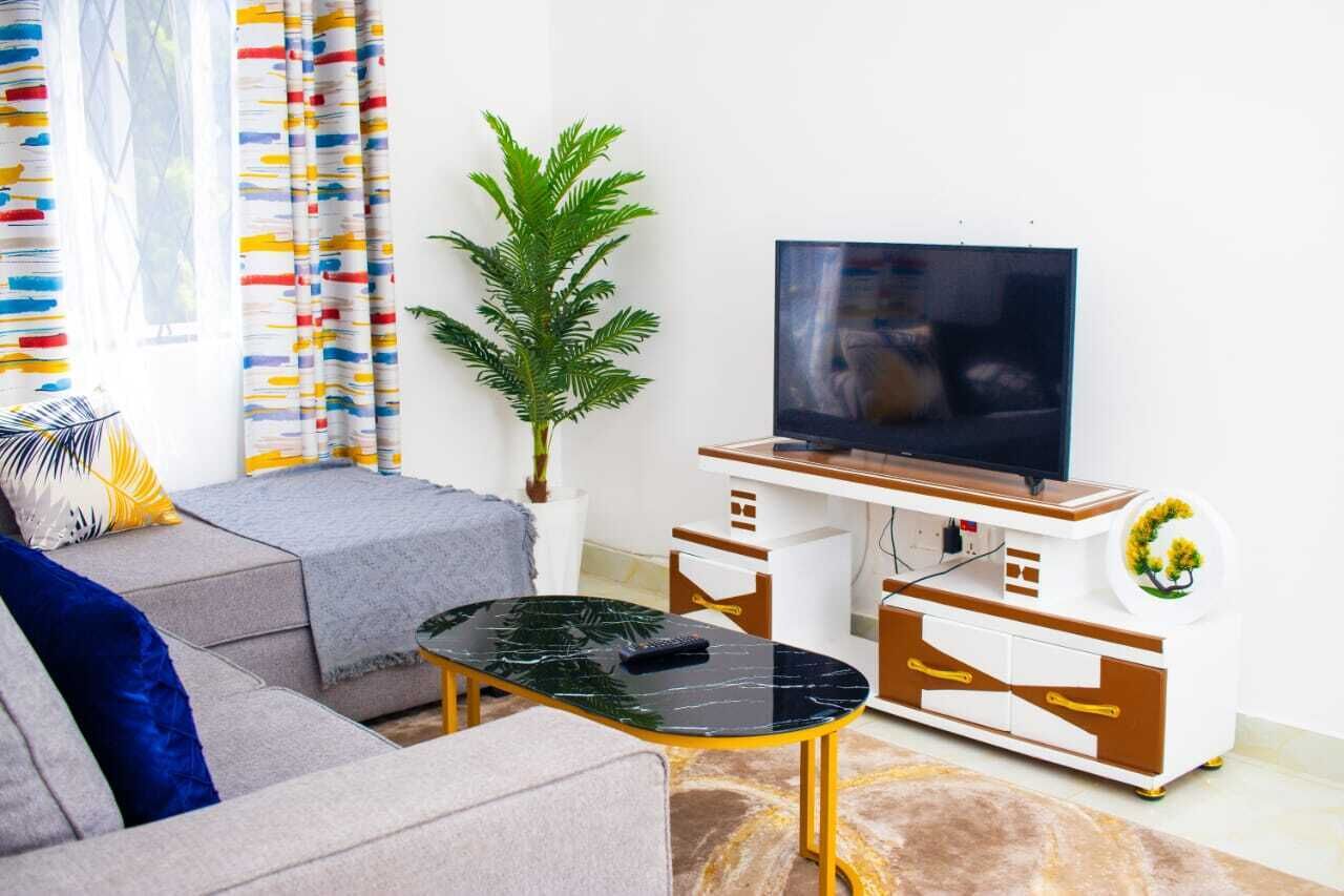 A living room with a sofa, a coffee table, a TV, and a plant.
