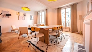 Un salon moderne avec une table à manger en bois, des chaises et une grande fenêtre agrémentée de rideaux.