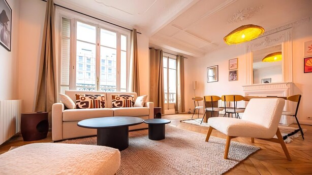 Un salon moderne comprenant un canapé, deux tables basses et un coin repas avec des chaises.