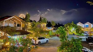 A nighttime view of a resort with multiple buildings, outdoor seating areas, and a paved driveway. - Finance Boutique (Kampot)