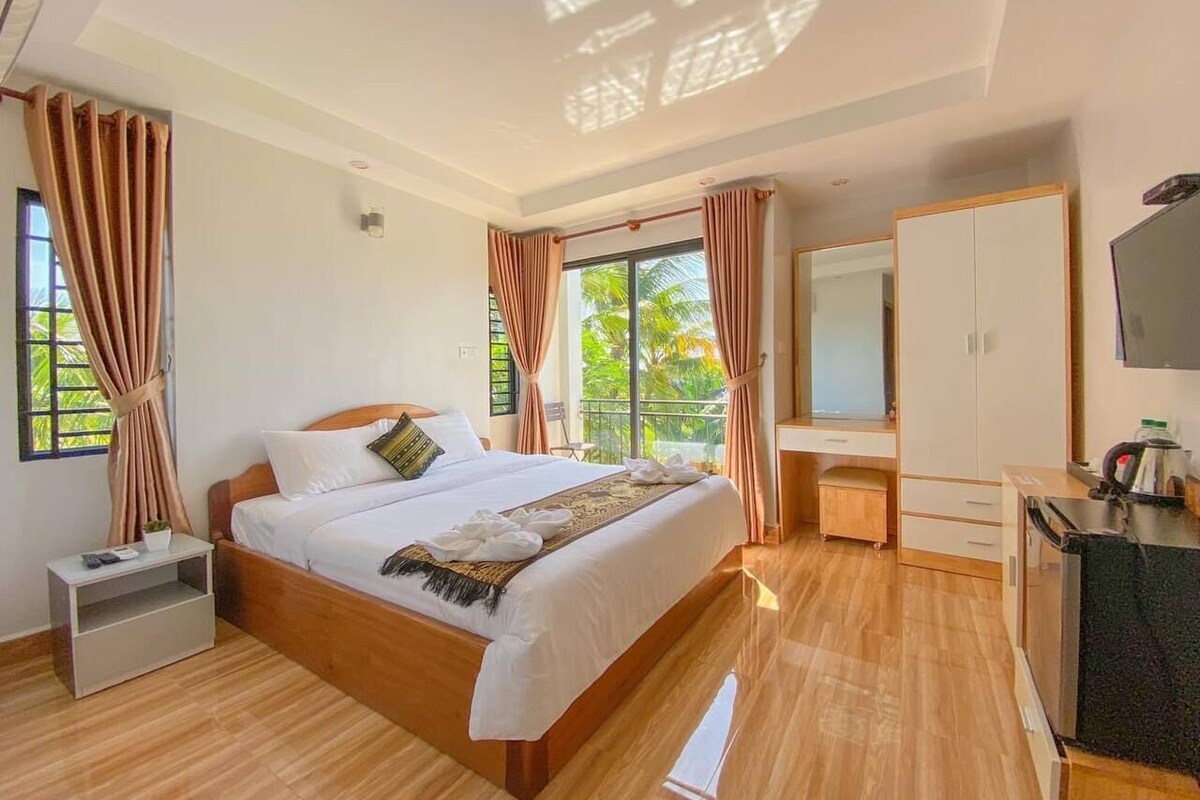 A modern hotel room with a large bed, a desk, a wardrobe, and a TV.