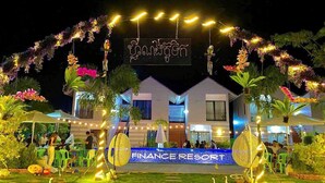 A resort with a sign reading "Finance Resort" and a well-lit entrance with string lights and floral decorations. - Finance Boutique (Kampot)