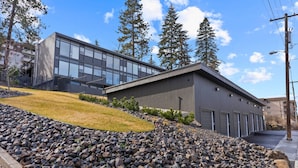 A modern building with a flat roof, large windows, and a gravel driveway.