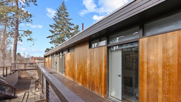 A modern building with wooden paneling, large windows, and a wooden deck.