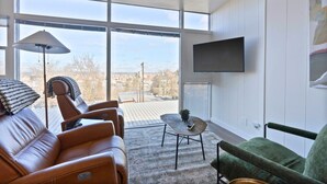 A modern living room with leather sofas, a small round table, and a large window offering a city view.