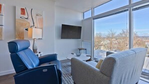 A modern living room with a large window, a flat-screen TV, and two sofas. - Historic Modern Apartment! Park Free w/ DT Views! (Spokane)