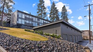 A modern building with a flat roof, large windows, and a gravel driveway. - Historic Modern Apartment! Park Free w/ DT Views! (Spokane)