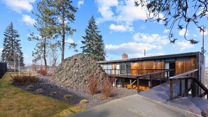 A modern building with a wooden deck, a stone wall, and a clear sky. - Historic Modern Apartment! Park Free w/ DT Views! (Spokane)