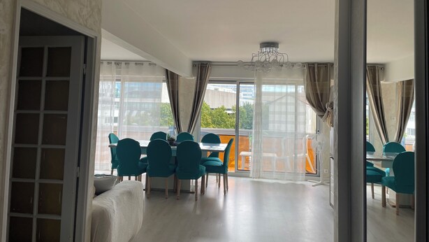Un'ampia stanza con zona pranzo, ampie finestre e vista sulla città.