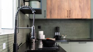A kitchen with a modern faucet, a sink, and a countertop with various items. - GuestReady - Lush Stay in Funchal (Funchal)