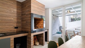 A modern kitchen with a built-in oven, wooden cabinetry, and a dining area with a table and chairs. - GuestReady - Lush Stay in Funchal (Funchal)