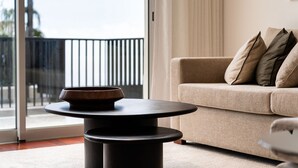 A modern living room with a sofa, a round table with a bowl, and a view through a glass door. - GuestReady - Lush Stay in Funchal (Funchal)
