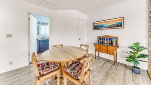 A dining area with a wooden table and chairs, a kitchen in the background, and a painting on the wall. - 1 Mi to Alto Lake: Mtn-View Home w/ Large Yard! (Alto)