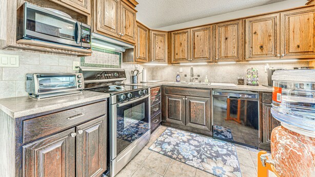 A kitchen with wooden cabinets, stainless steel appliances, a built-in microwave, and a dishwasher. - 1 Mi to Alto Lake: Mtn-View Home w/ Large Yard! (Alto)