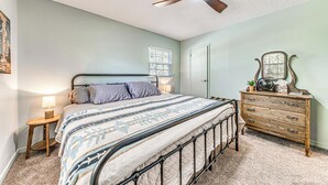 A bedroom with a bed, bedside table, dresser, and ceiling fan. - 1 Mi to Alto Lake: Mtn-View Home w/ Large Yard! (Alto)