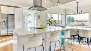 Een moderne keuken met witte kastjes, roestvrijstalen apparatuur en een centraal eiland met barstoelen.